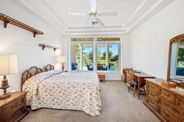 carpeted bedroom with ceiling fan and a tray ceiling