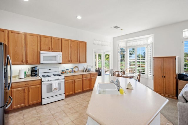 kitchen with light tile patterned floors, a center island with sink, decorative light fixtures, white appliances, and sink