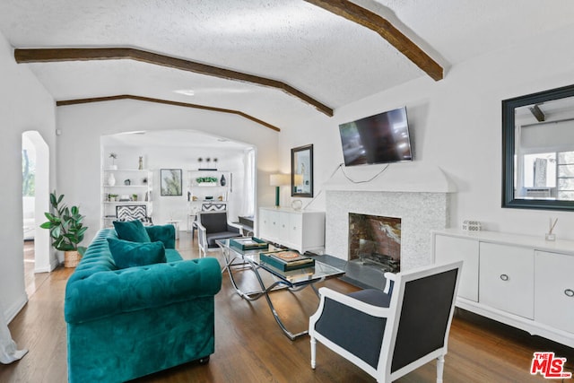 living room with a textured ceiling, dark hardwood / wood-style flooring, and vaulted ceiling with beams