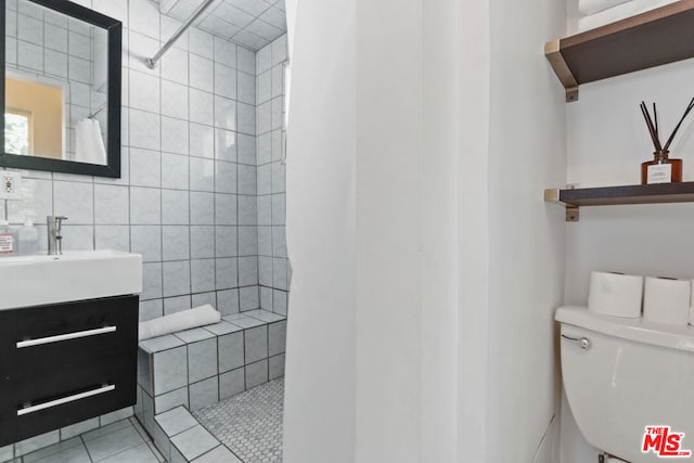 bathroom featuring toilet, a shower with shower curtain, tile walls, tile patterned floors, and vanity