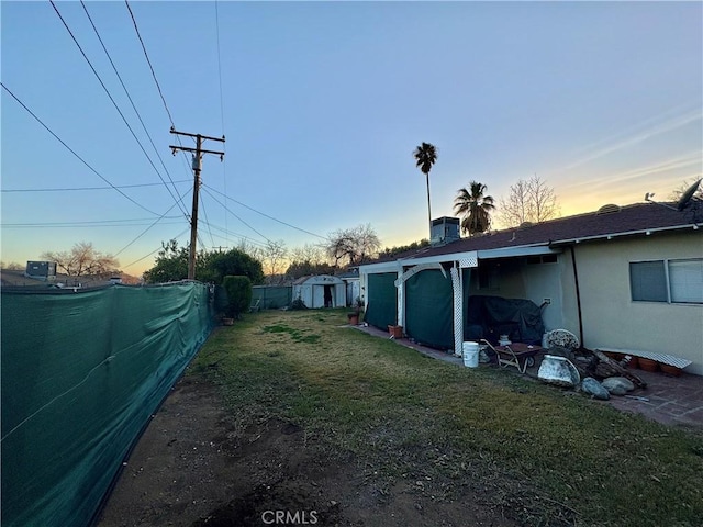 yard at dusk featuring a storage unit