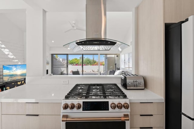 kitchen with stainless steel range, light brown cabinets, island exhaust hood, and fridge