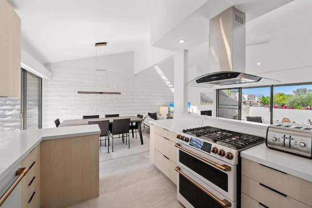 kitchen with island exhaust hood, light brown cabinetry, lofted ceiling, pendant lighting, and gas range oven