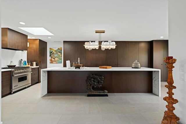 kitchen featuring a skylight, dark brown cabinets, hanging light fixtures, and high end range