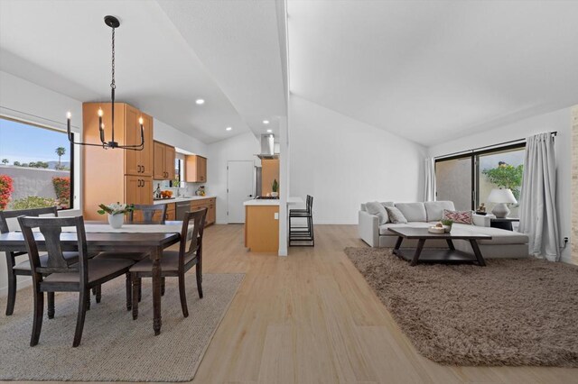 dining area with light wood-type flooring, lofted ceiling, and an inviting chandelier