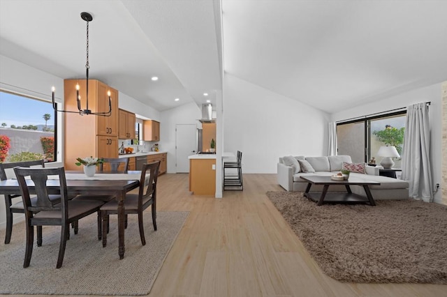 dining area with light wood-type flooring, an inviting chandelier, and lofted ceiling