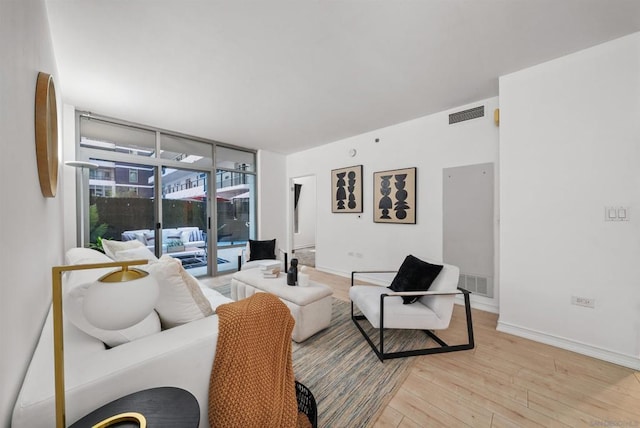 living room with expansive windows and light hardwood / wood-style flooring