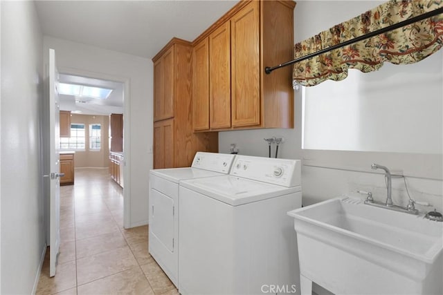 clothes washing area featuring cabinets, light tile patterned flooring, washer and clothes dryer, and sink