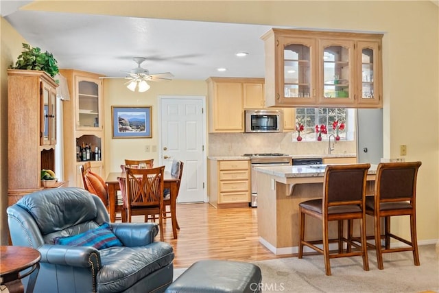 kitchen featuring ceiling fan, light brown cabinets, appliances with stainless steel finishes, and tasteful backsplash