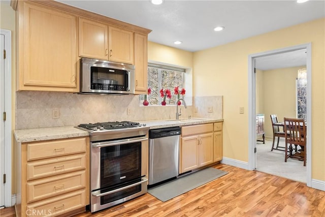 kitchen featuring light hardwood / wood-style floors, decorative backsplash, sink, light brown cabinets, and stainless steel appliances