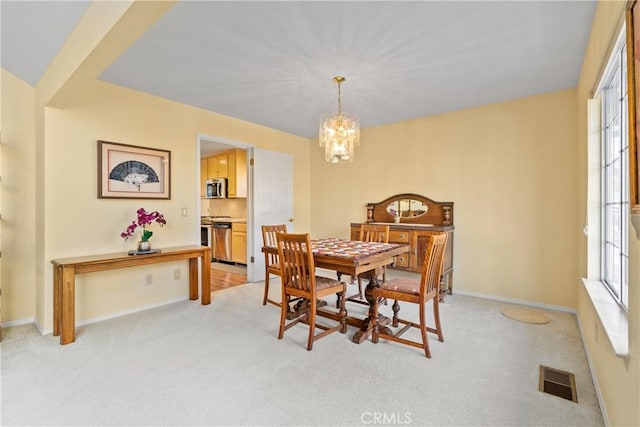 dining space featuring light carpet and a notable chandelier