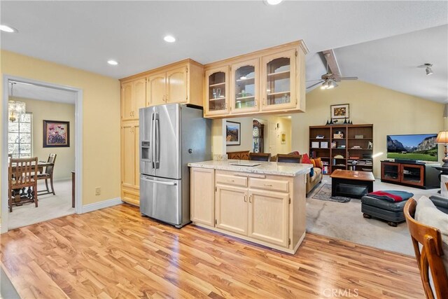 kitchen with vaulted ceiling with beams, stainless steel fridge, kitchen peninsula, ceiling fan, and light hardwood / wood-style flooring