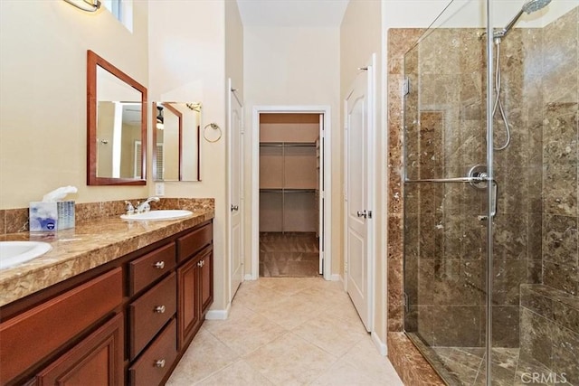 bathroom featuring double vanity, a shower stall, a walk in closet, and a sink