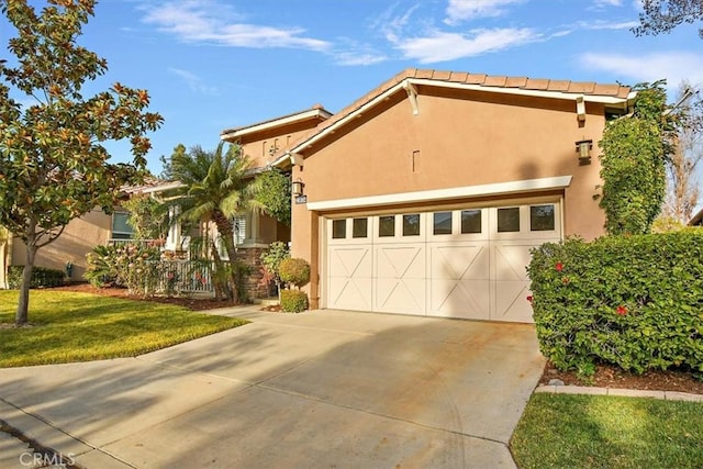 view of front facade featuring a front yard, an attached garage, driveway, and stucco siding