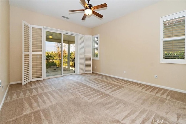 carpeted empty room featuring baseboards, visible vents, and ceiling fan