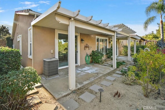 back of property with stucco siding, cooling unit, and a patio