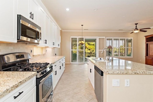 kitchen featuring a kitchen island with sink, ornamental molding, a sink, tasteful backsplash, and stainless steel appliances