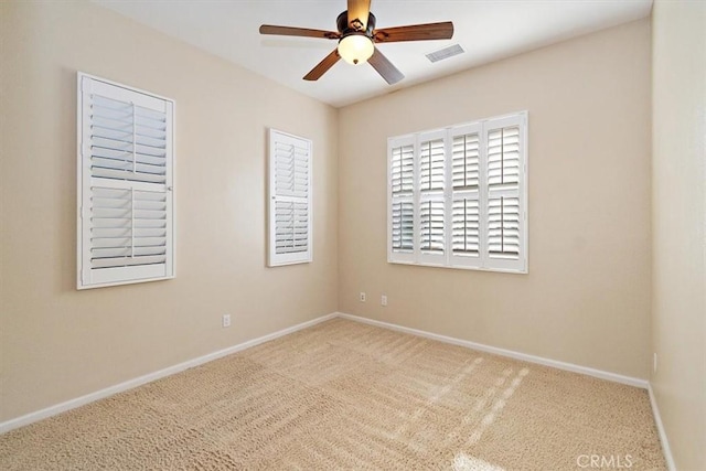 spare room with a ceiling fan, carpet flooring, visible vents, and baseboards