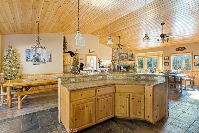 kitchen with pendant lighting, a center island, a fireplace, light stone counters, and wooden ceiling