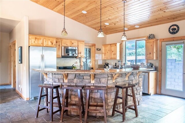 kitchen featuring wood ceiling, light brown cabinets, stainless steel appliances, hanging light fixtures, and a breakfast bar