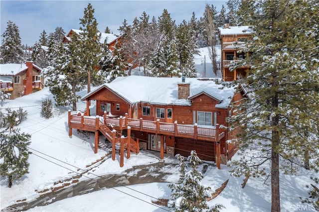 snow covered rear of property featuring a deck