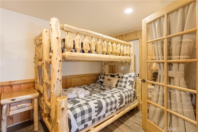 bedroom featuring hardwood / wood-style floors and wooden walls