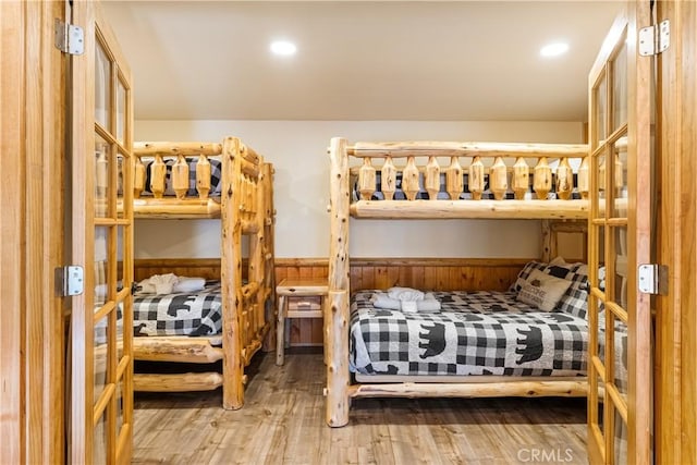 bedroom with wood-type flooring and wooden walls