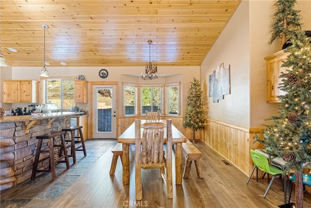 dining area with an inviting chandelier, wood ceiling, light hardwood / wood-style floors, wooden walls, and vaulted ceiling