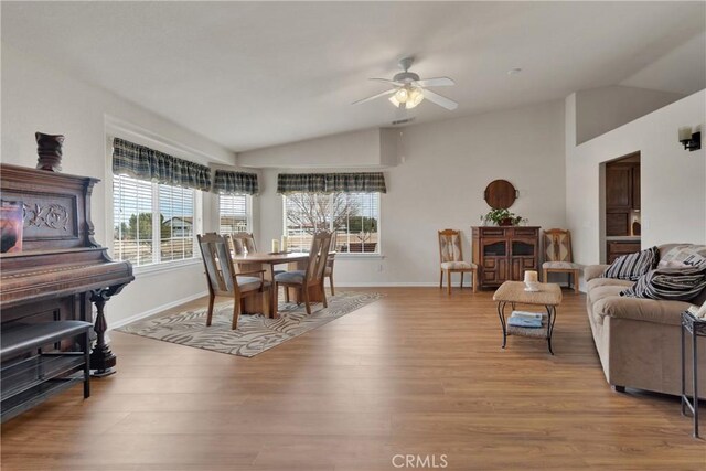 living room with ceiling fan, vaulted ceiling, and light hardwood / wood-style flooring