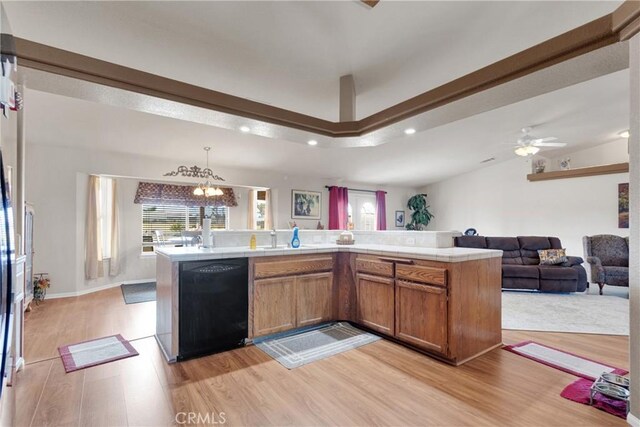 kitchen with ceiling fan with notable chandelier, decorative light fixtures, black dishwasher, sink, and light hardwood / wood-style flooring