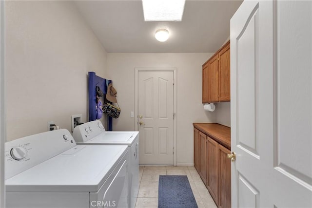 laundry room featuring light tile patterned flooring, washing machine and clothes dryer, and cabinets