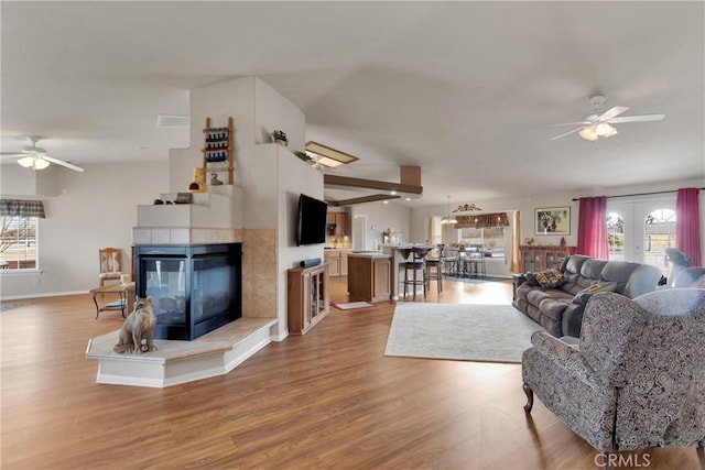 living room with ceiling fan, hardwood / wood-style floors, and a tile fireplace