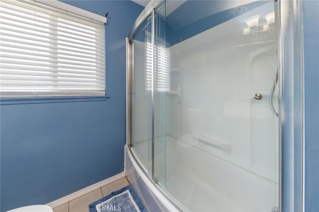 bathroom with combined bath / shower with glass door, tile patterned floors, and toilet