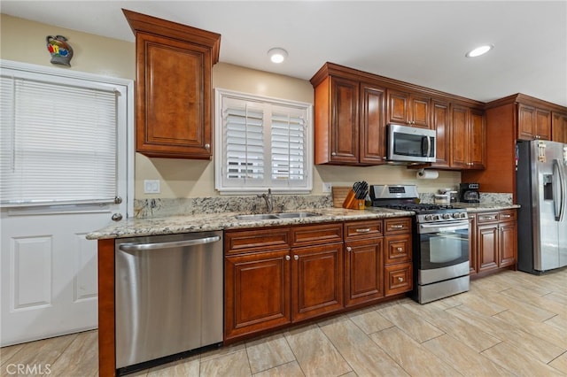 kitchen featuring light stone countertops, sink, and stainless steel appliances