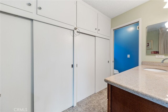 bathroom with a textured ceiling, toilet, and vanity