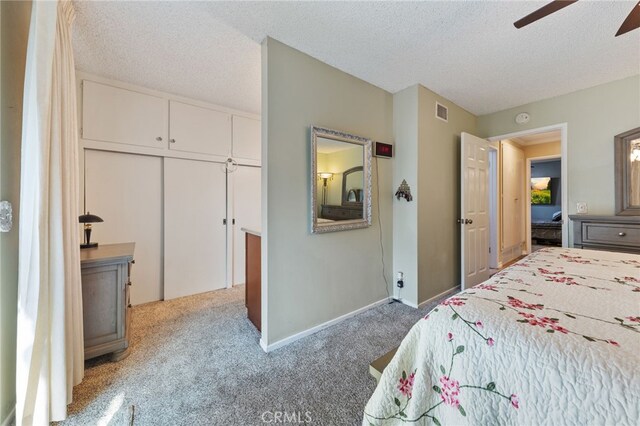 carpeted bedroom with a textured ceiling, ceiling fan, and a closet