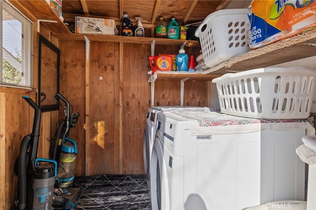 laundry room with wood walls and washing machine and clothes dryer