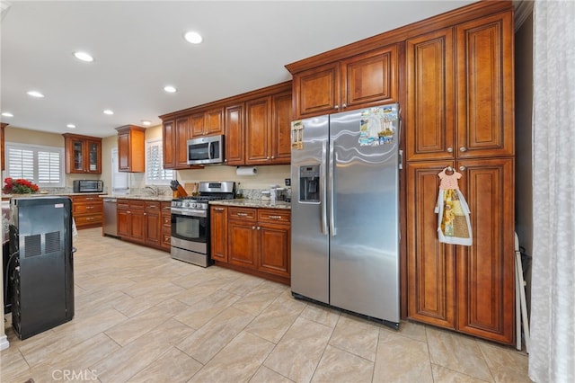 kitchen with light stone countertops, sink, and stainless steel appliances