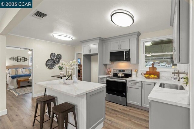 kitchen with light stone counters, sink, stainless steel electric stove, and gray cabinets