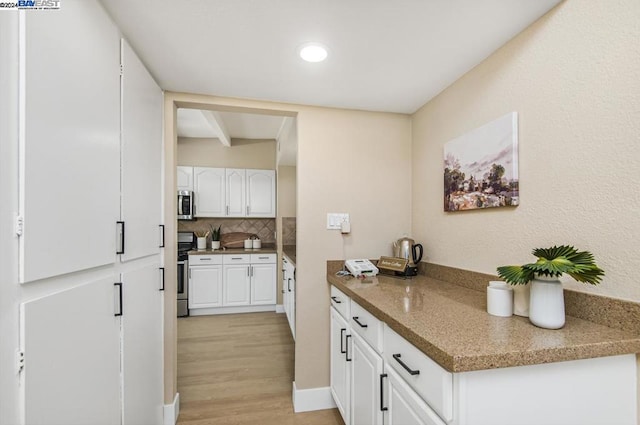 kitchen featuring dark stone countertops, white cabinetry, appliances with stainless steel finishes, light hardwood / wood-style flooring, and backsplash