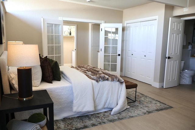 bedroom featuring ensuite bathroom, a closet, hardwood / wood-style floors, and french doors