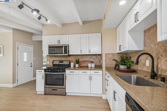 kitchen featuring stainless steel appliances, sink, white cabinetry, light hardwood / wood-style flooring, and beam ceiling