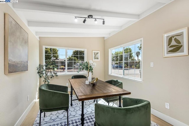 dining space featuring light wood-type flooring and beamed ceiling