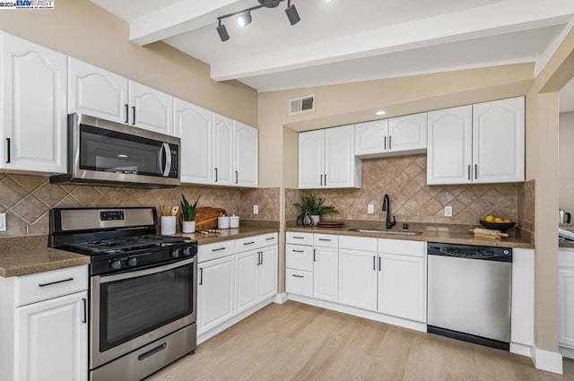 kitchen with stainless steel appliances, sink, white cabinetry, vaulted ceiling with beams, and backsplash