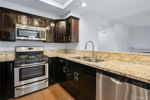 kitchen with sink, dark brown cabinets, light hardwood / wood-style flooring, appliances with stainless steel finishes, and light stone countertops