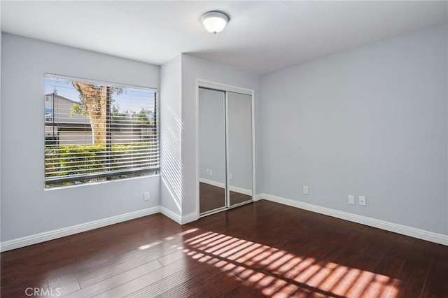 unfurnished bedroom with dark hardwood / wood-style flooring and a closet