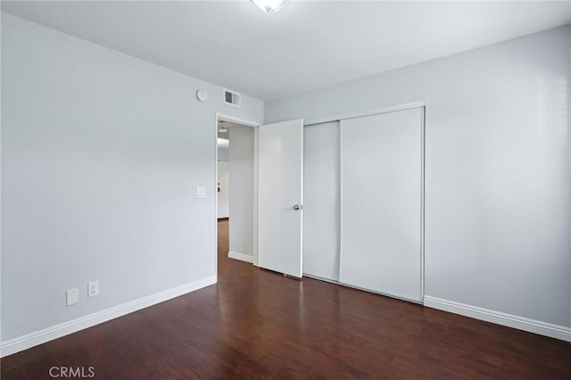 unfurnished bedroom with dark hardwood / wood-style flooring and a closet