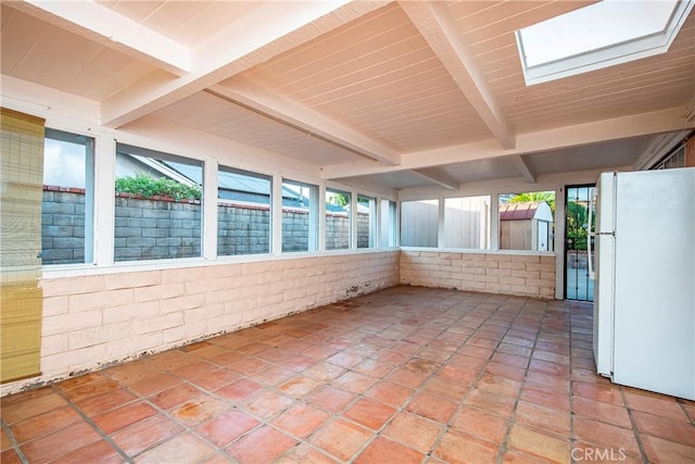 unfurnished sunroom featuring beamed ceiling