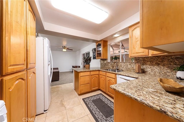 kitchen with kitchen peninsula, ceiling fan, white appliances, light stone countertops, and sink