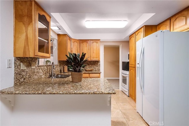 kitchen with light tile patterned floors, a tray ceiling, white fridge with ice dispenser, stone counters, and sink